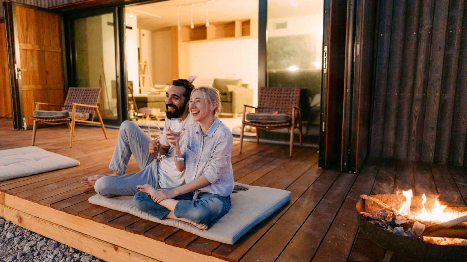 A couple enjoying their time on the deck next to a firepit
