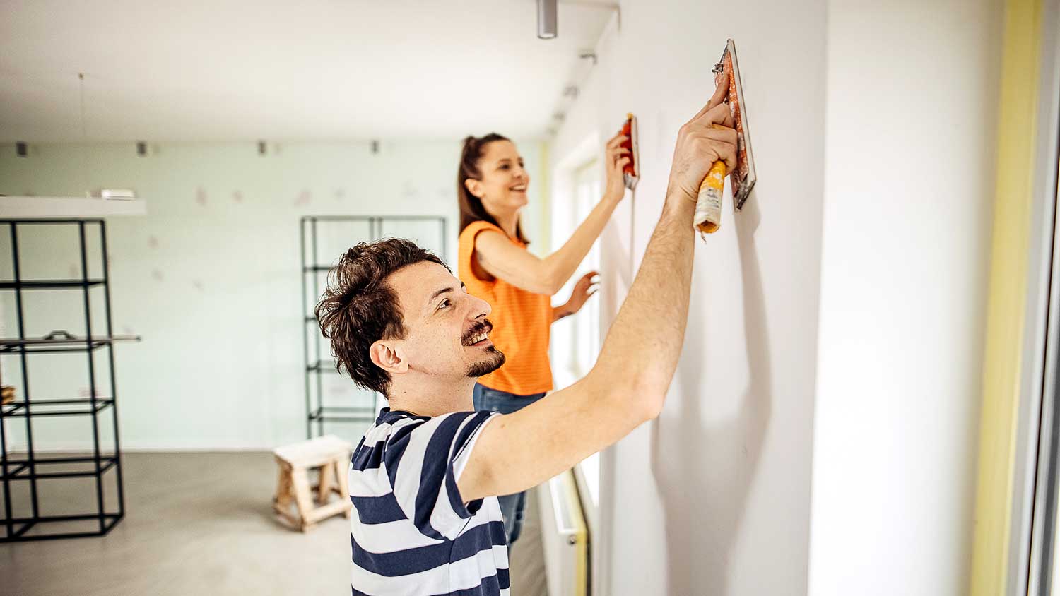 Couple using sanding blocks to prep an interior wall