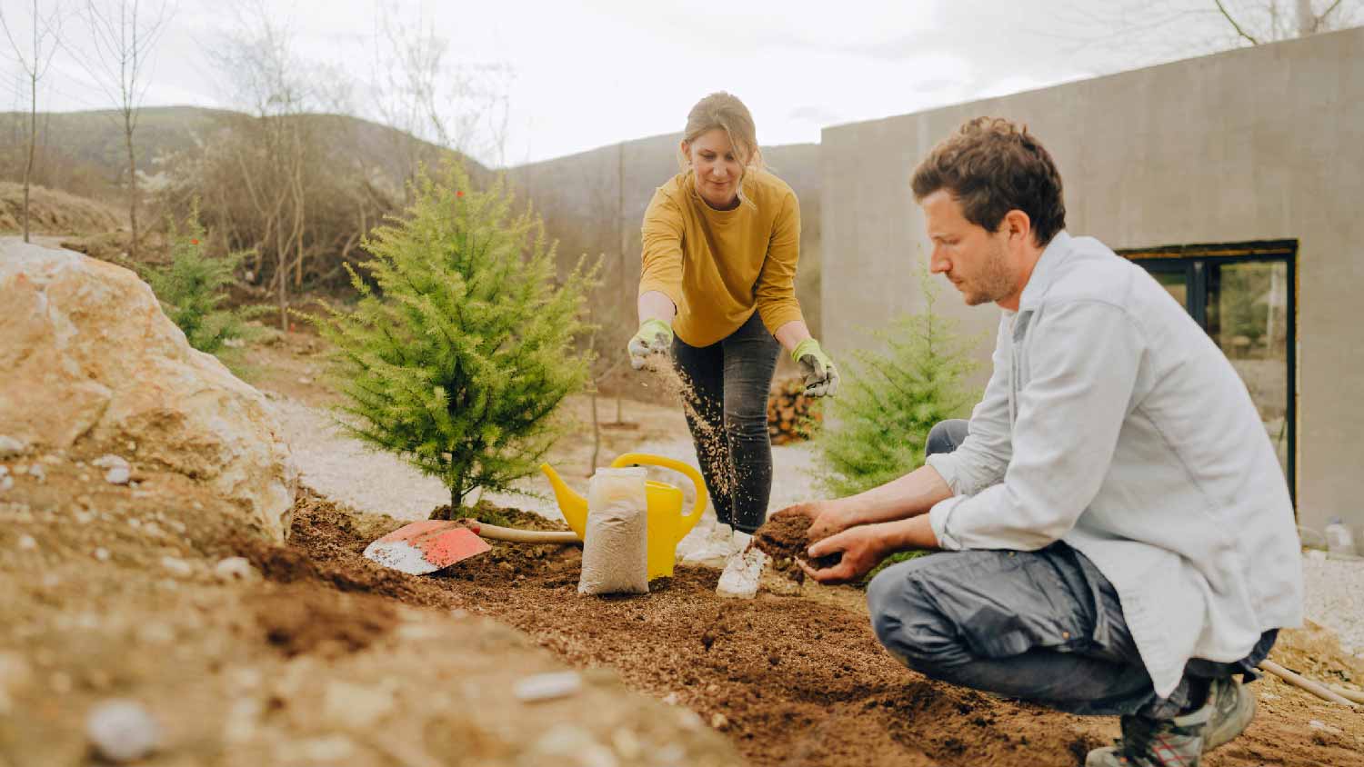 A couple seeding with lawn their garden