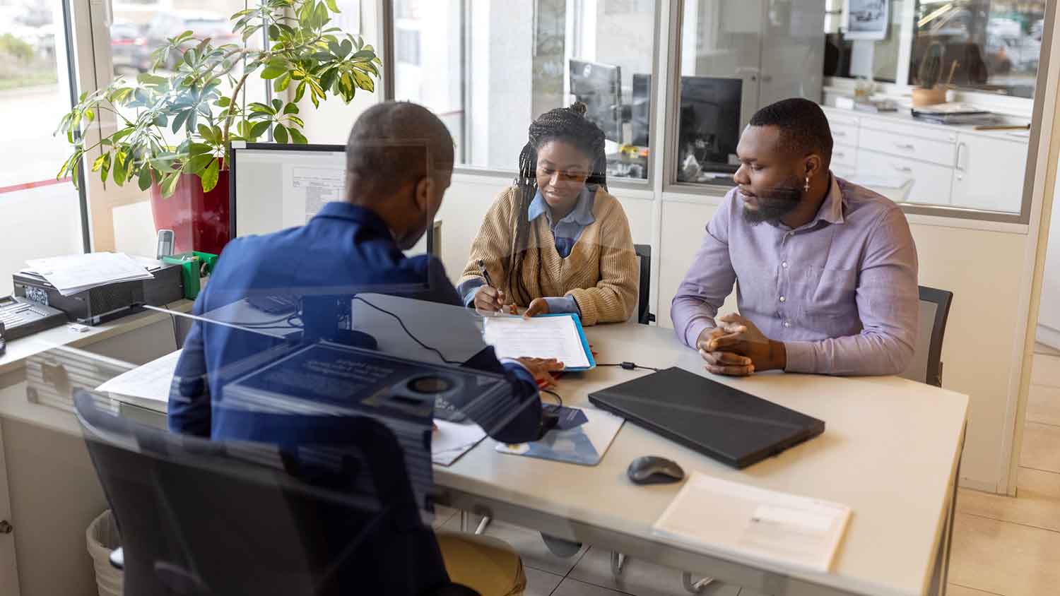 Couple at lender office signing mortgage agreement