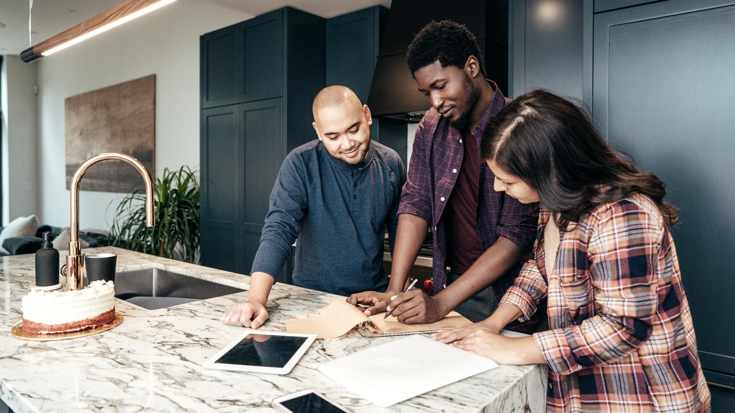 A young couple talking with a contractor in their kitchen