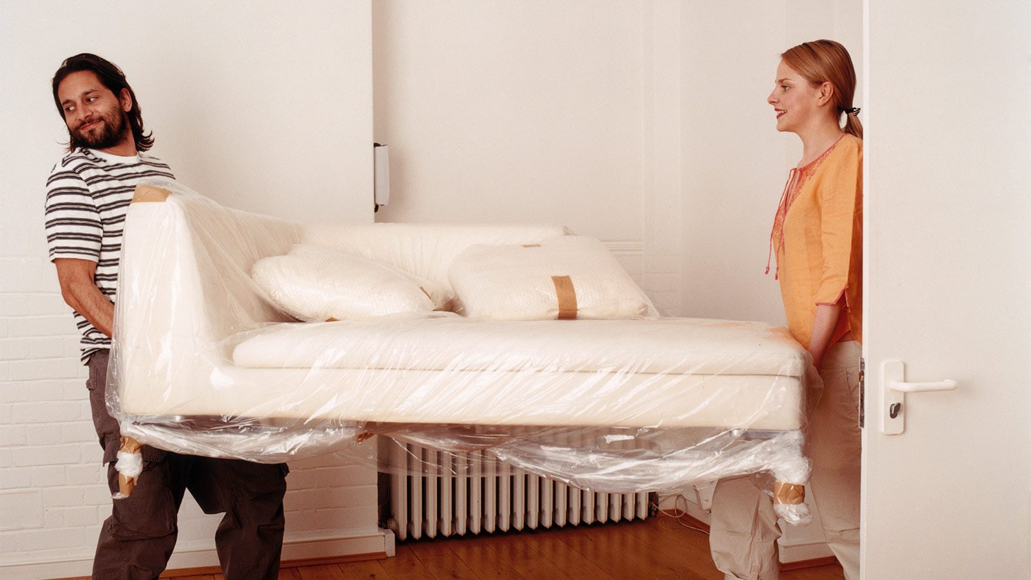 Couple moving white wrapped up couch