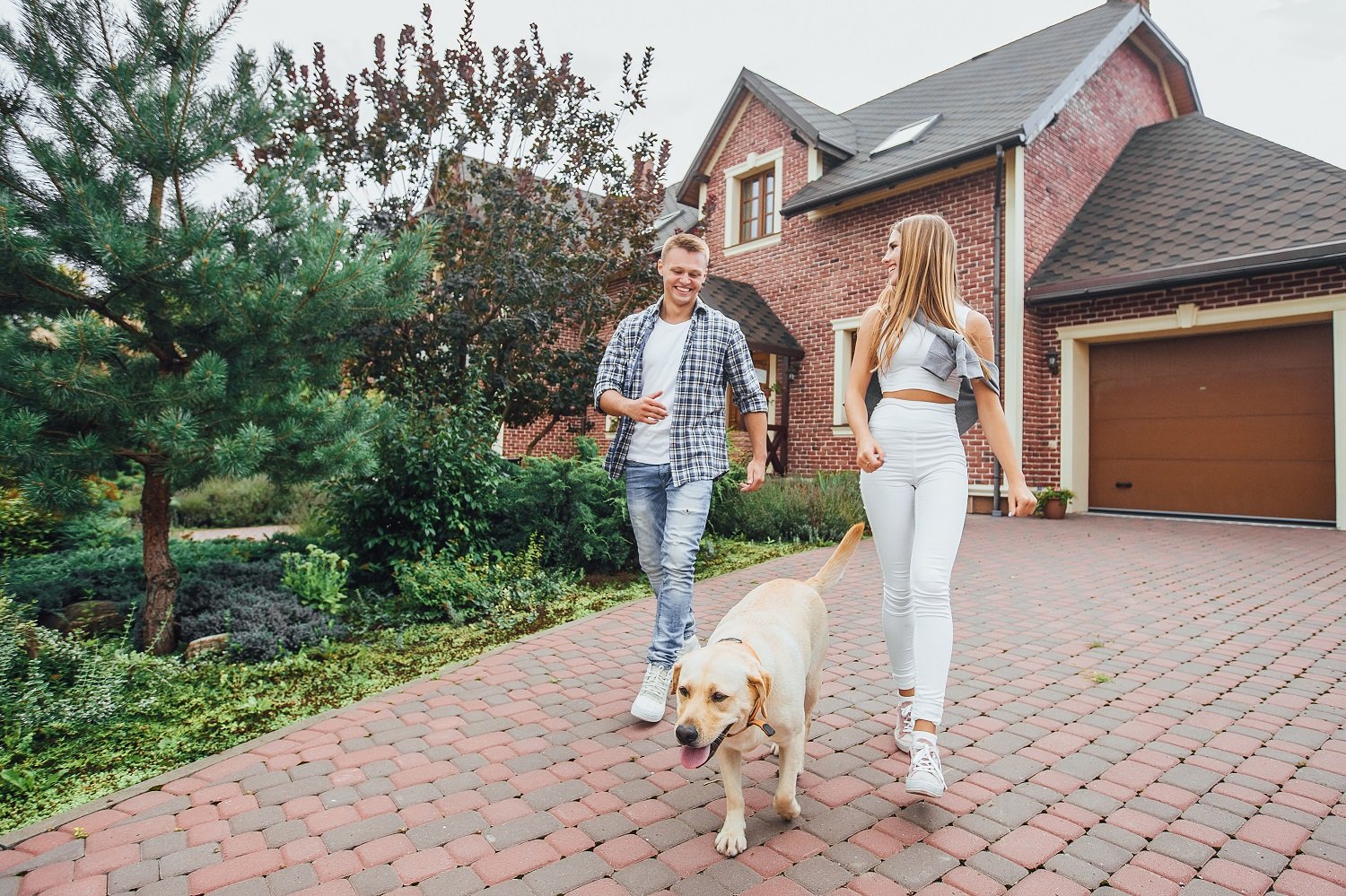 Young couple walks away from their house with their dog