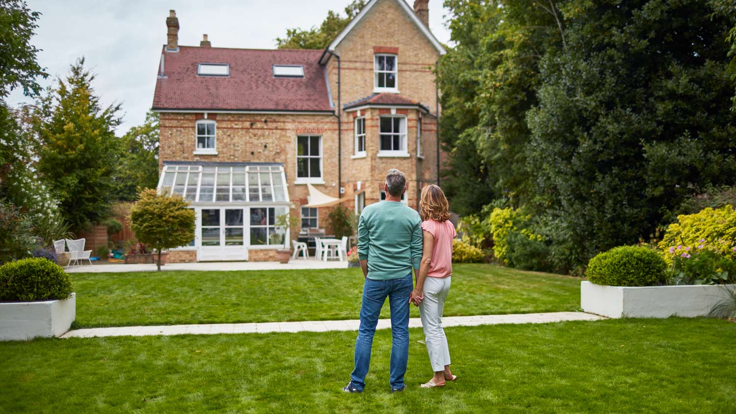 Couple on a garden looking at a house