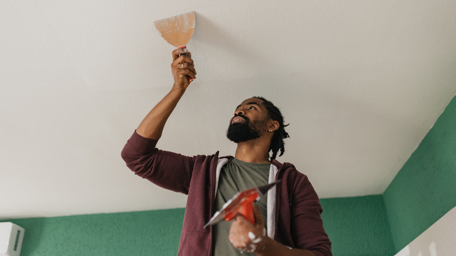 A man covering up the ceiling with plaster