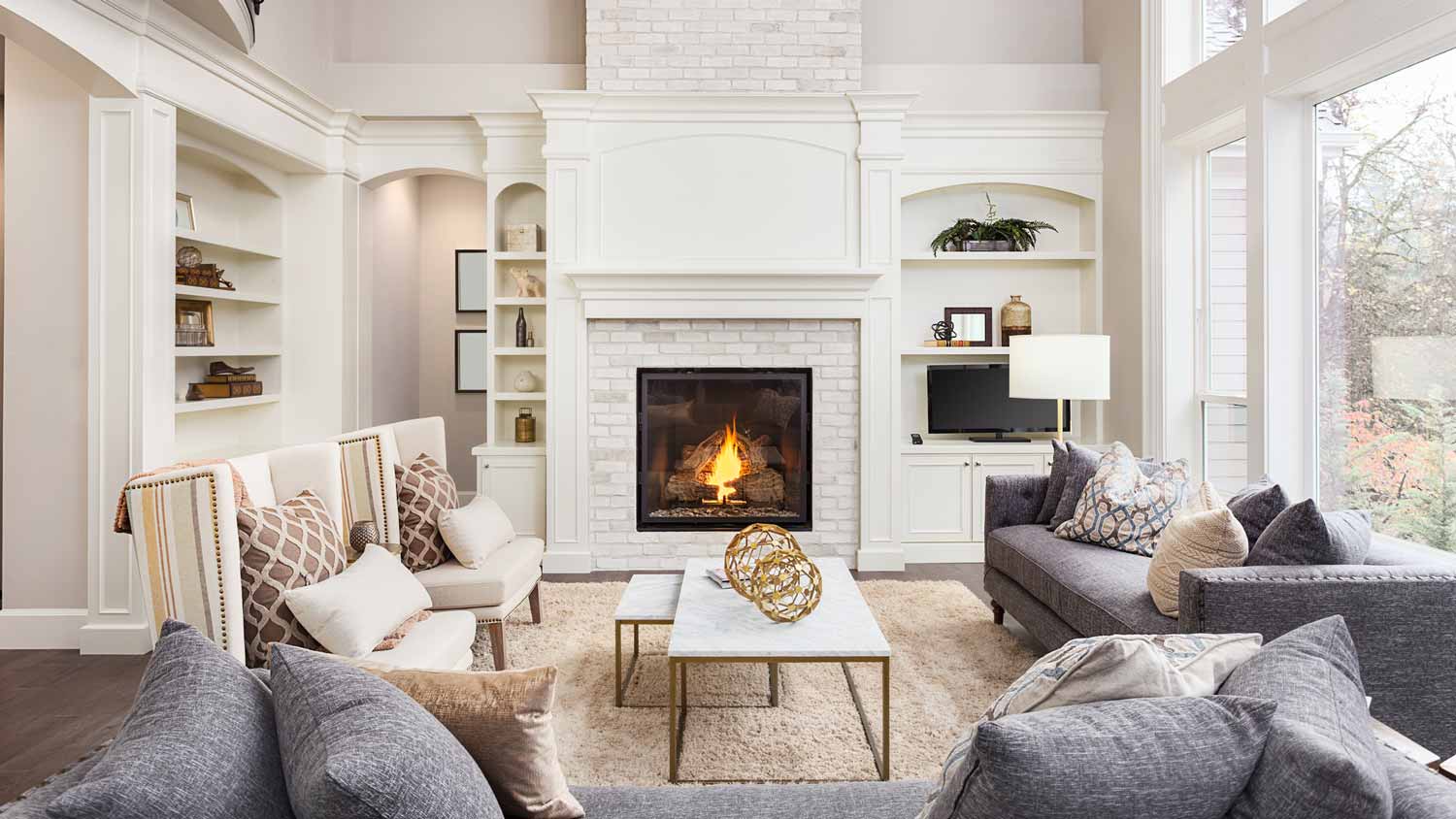 A cozy living room with a burning fireplace in the center of it