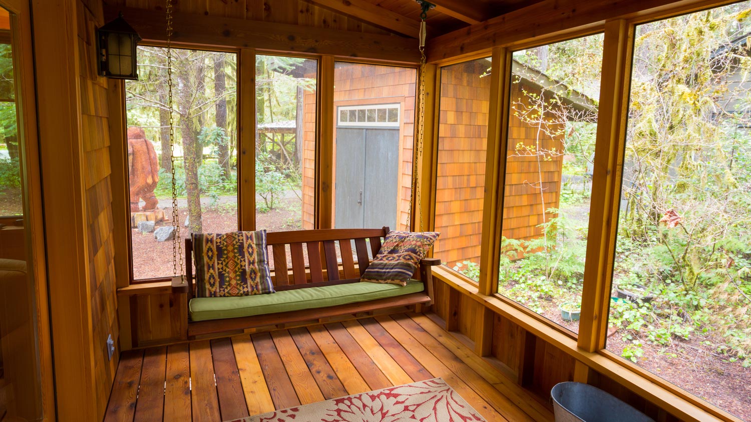 A swing in a cozy screened wooden porch