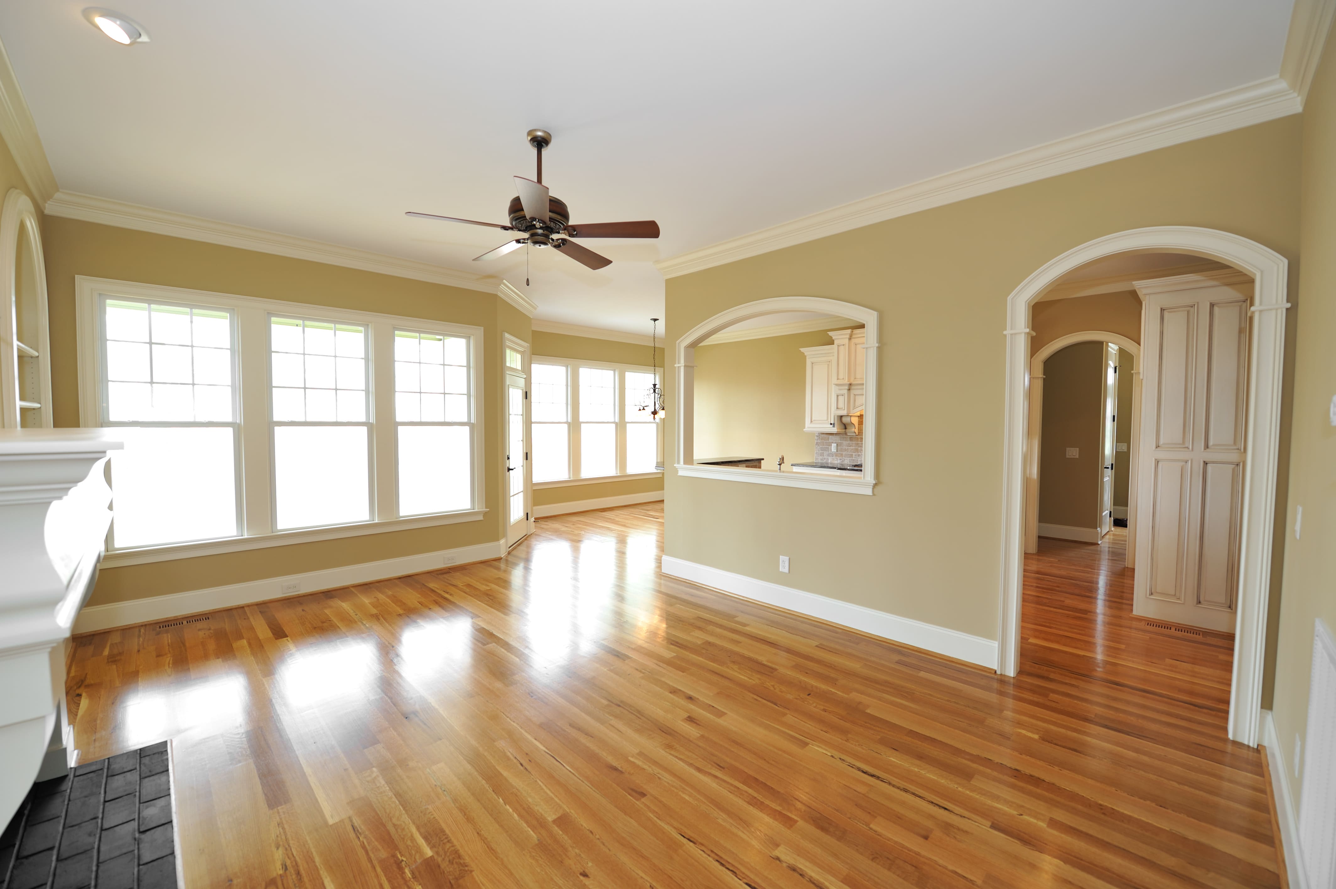 A brightly lit living room with crown molding around each archway