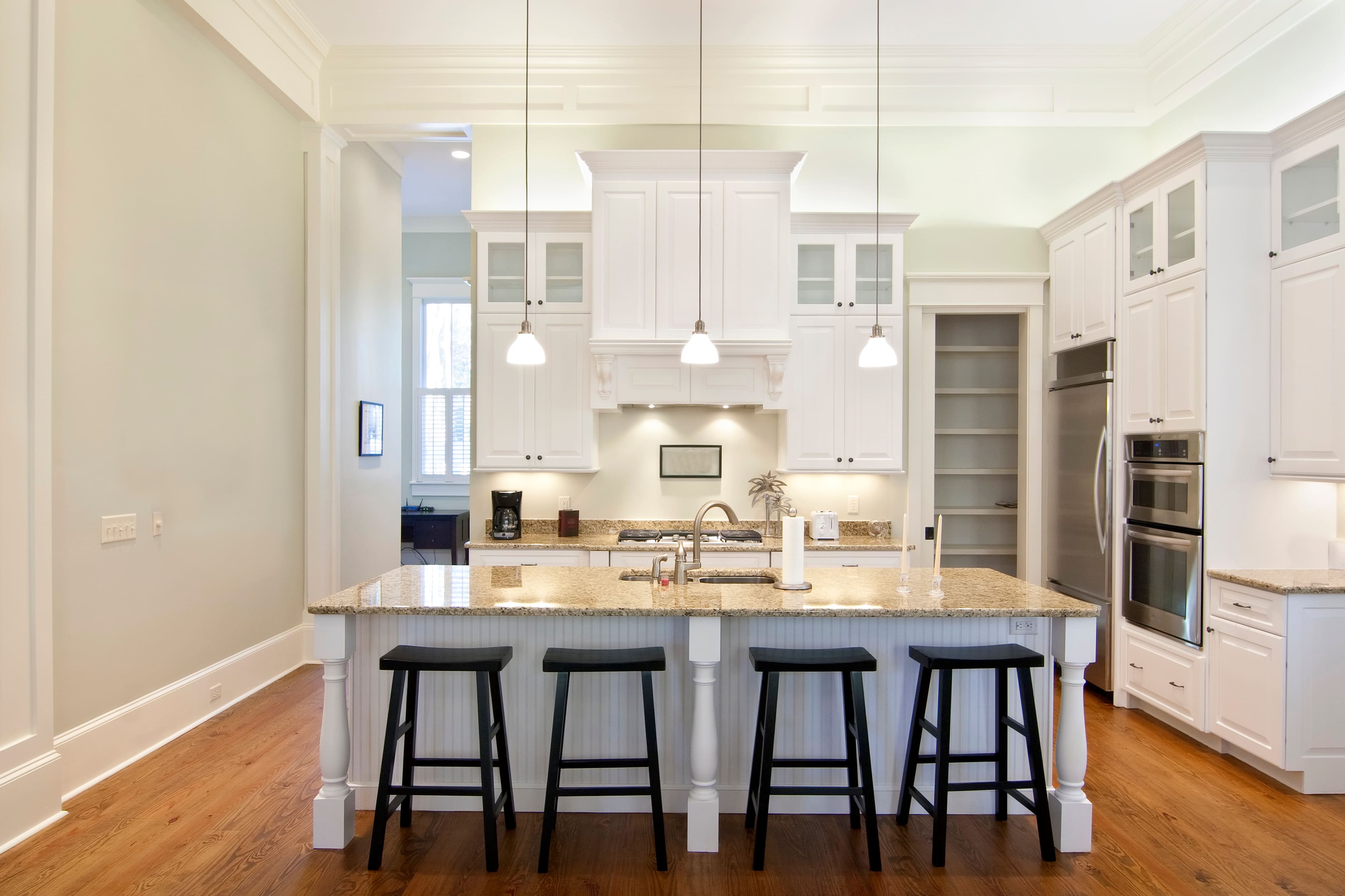 A brightly lit kitchen with white crown molding on the cabinet tops 