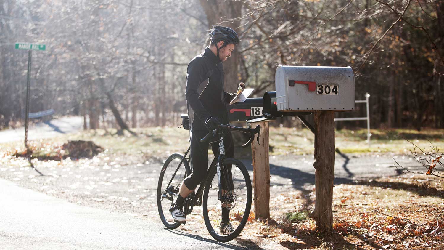 Cyclist picking up letters from his mailbox