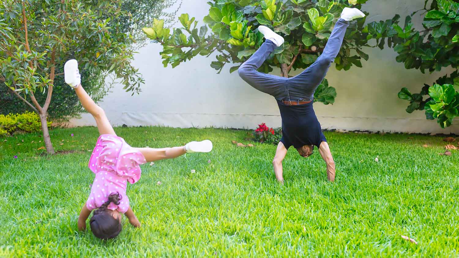 Daughter and father doing cartwheels in the yard