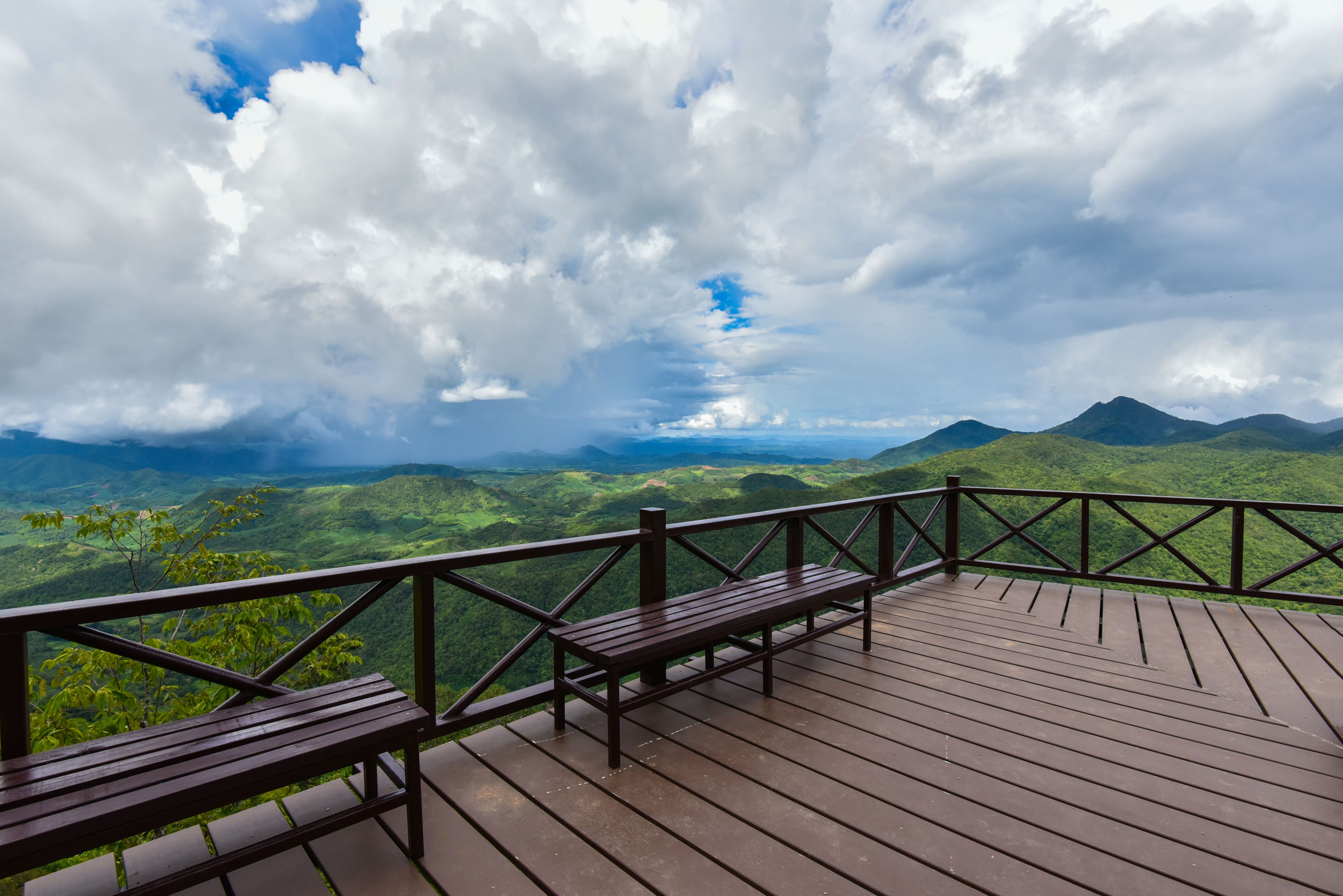 Patio overlooking mountain landscape with wooden railing and two benches