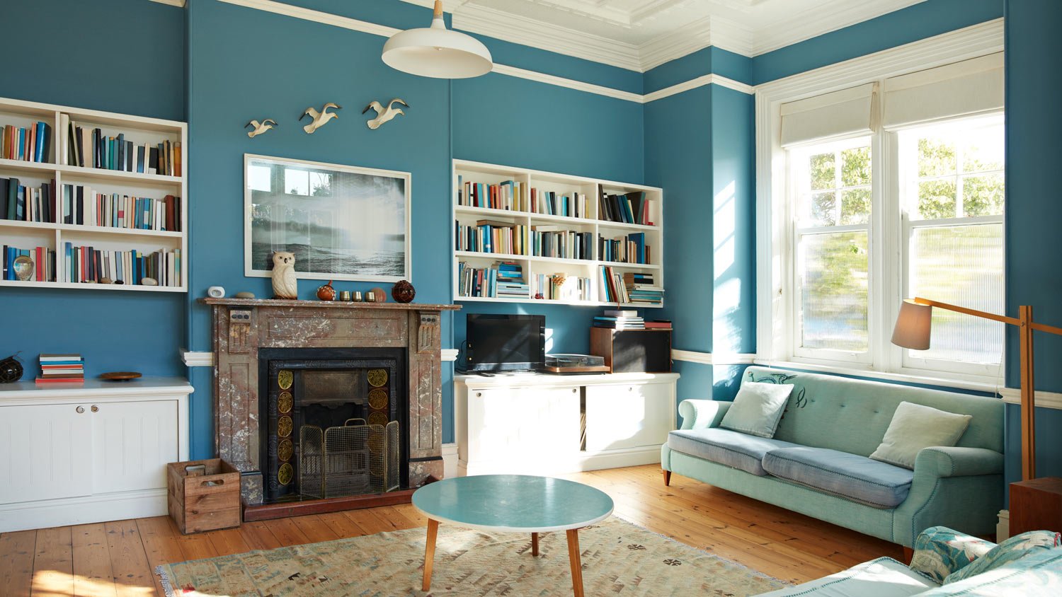 Bookshelf and fireplace in blue painted living room.
