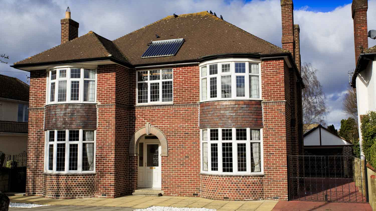 A detached brick house with bow windows