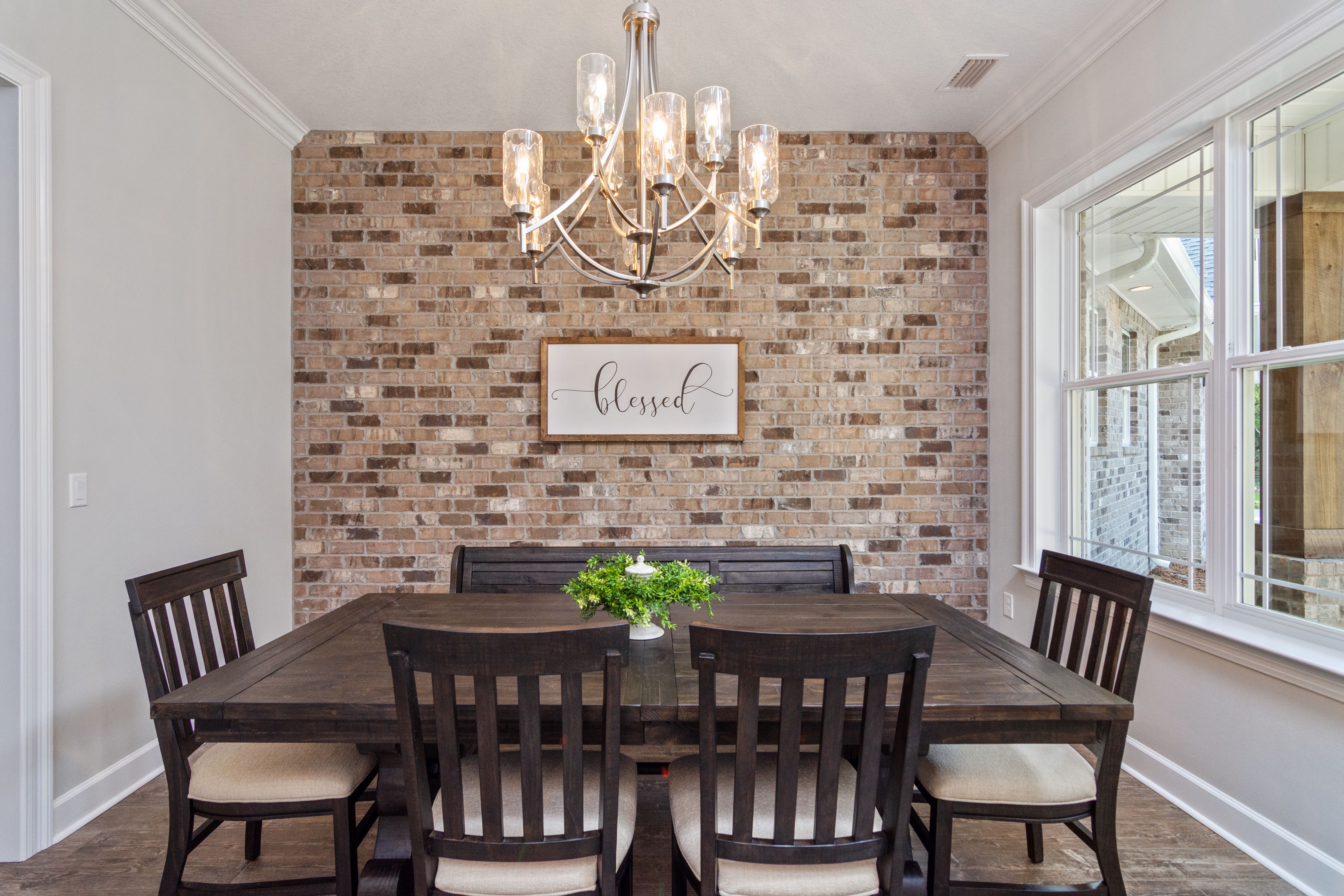 A dining room with a brick wall and votive chandelier 