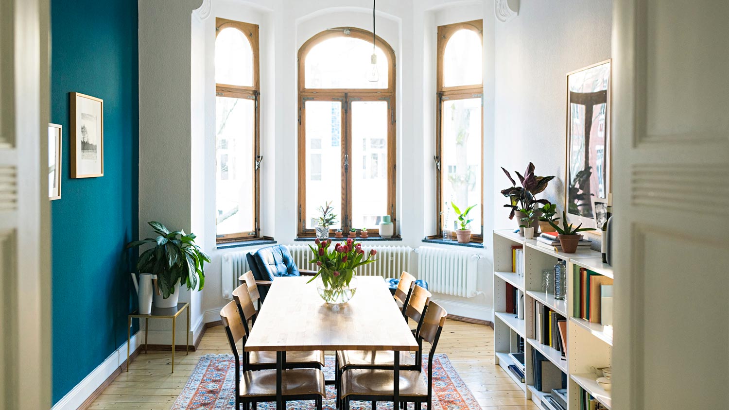 A dining room with a wooden table and large windows