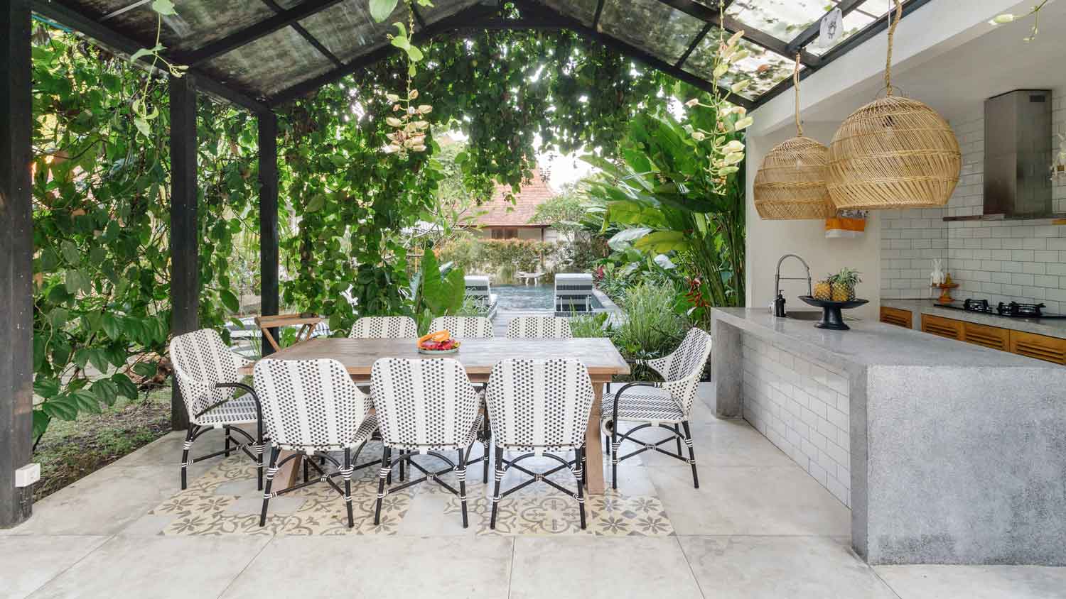 A dining table and chairs next to an outdoor kitchen