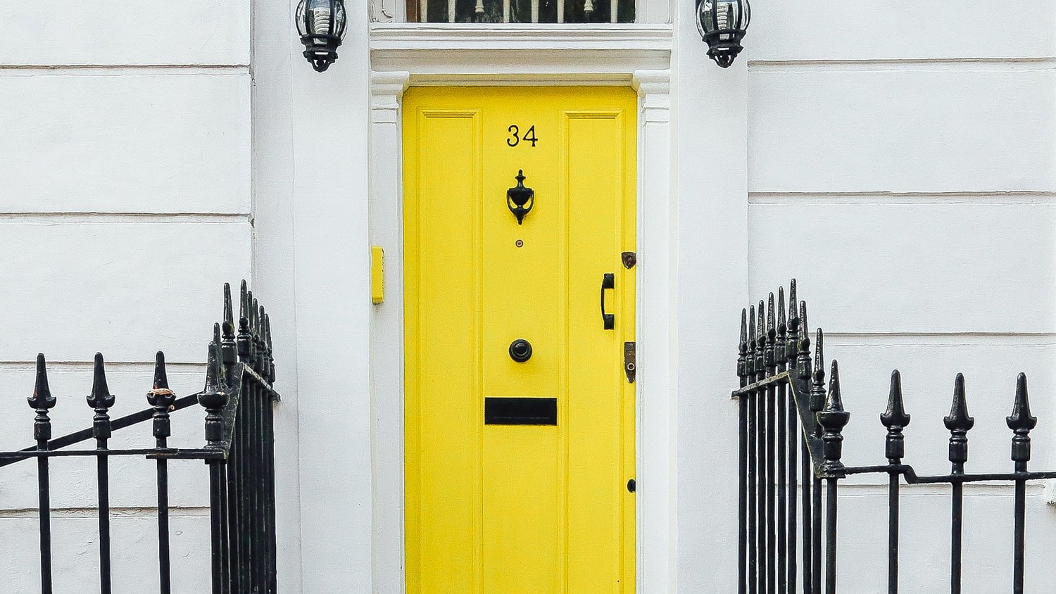 white home with bright yellow door with black fixtures