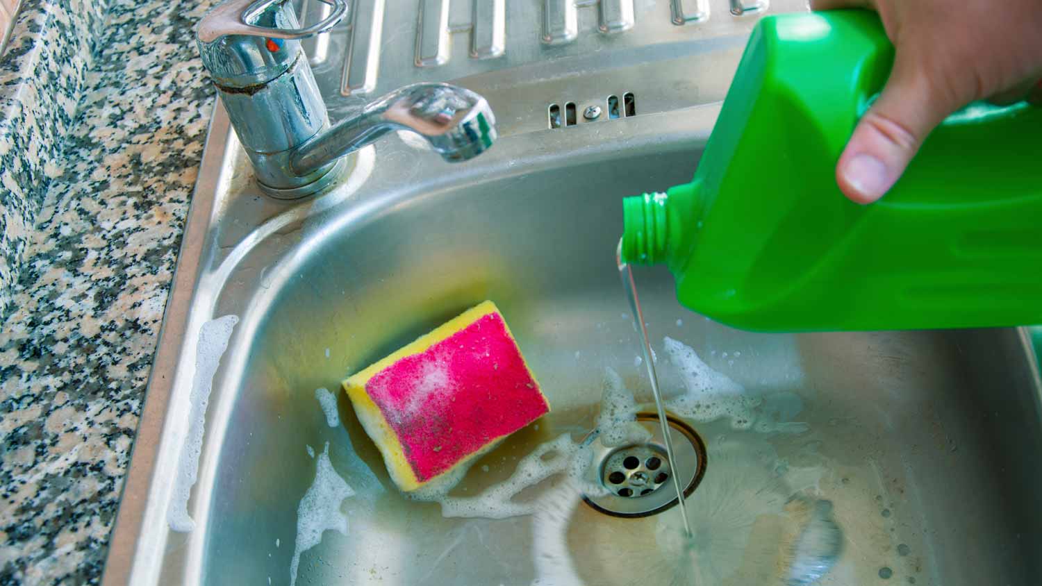 A hand disposing bleach in a sink