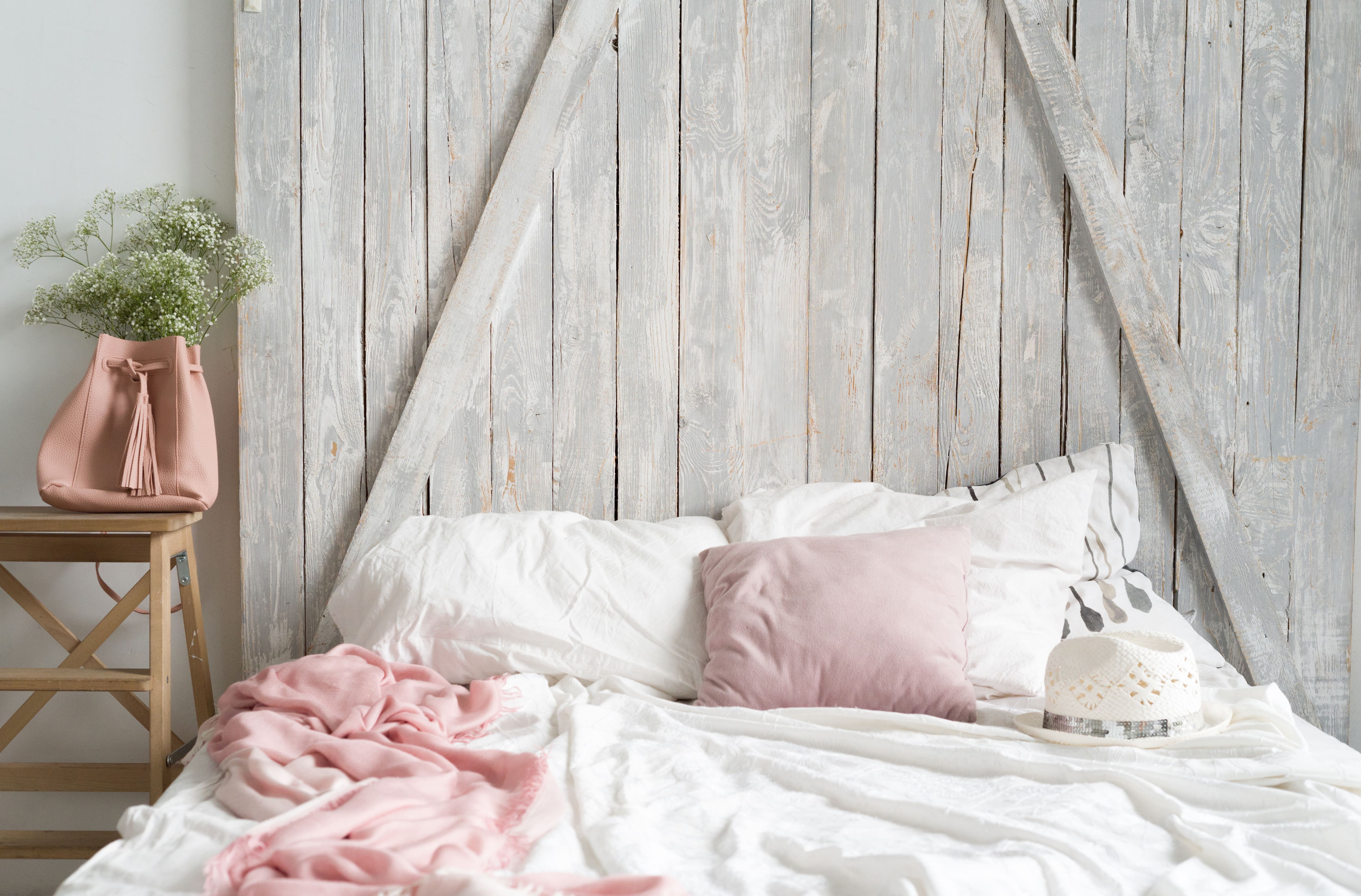 A white and pink bed set up in front of a barn door headboard