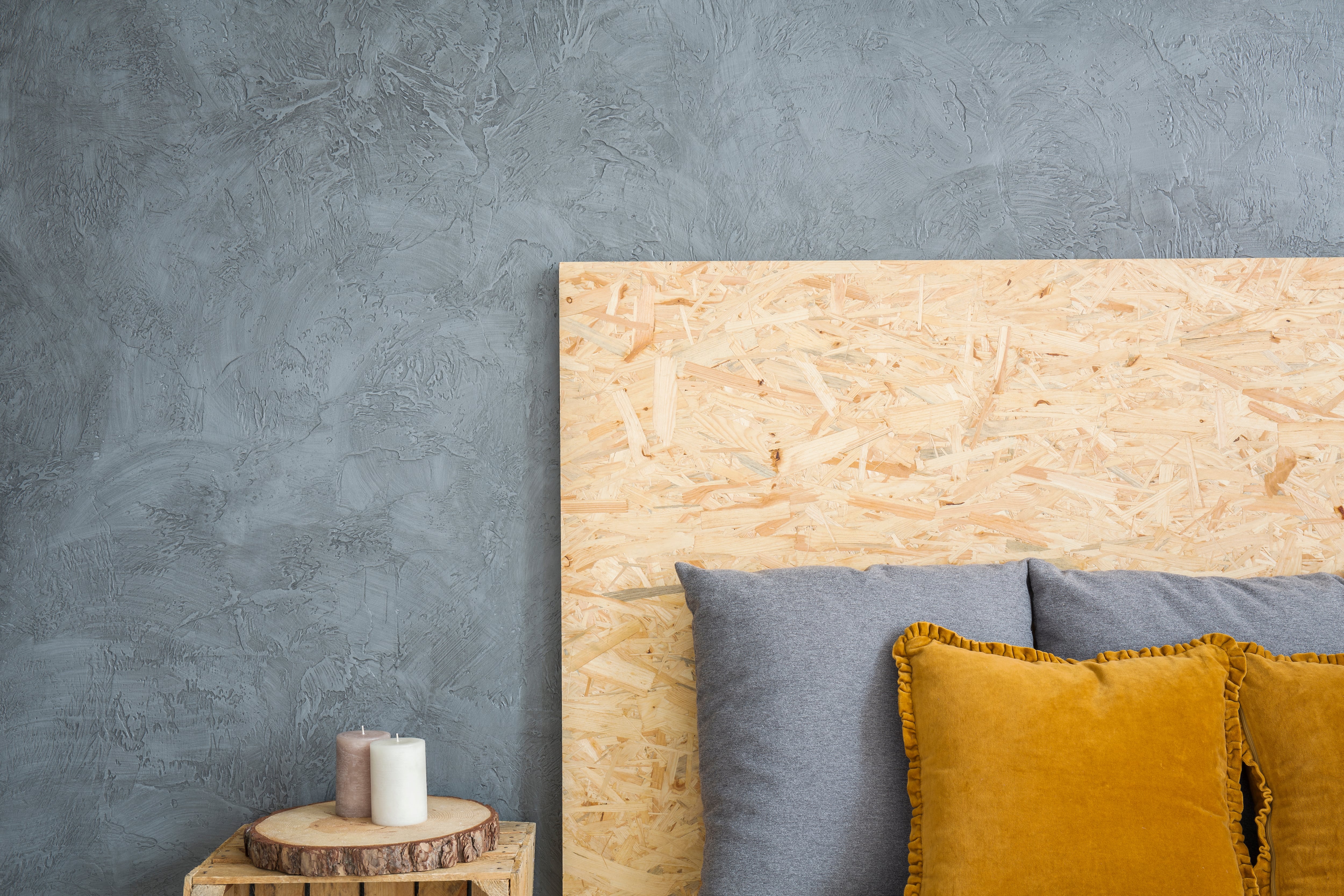 A gray bedroom with a headboard made from plywood