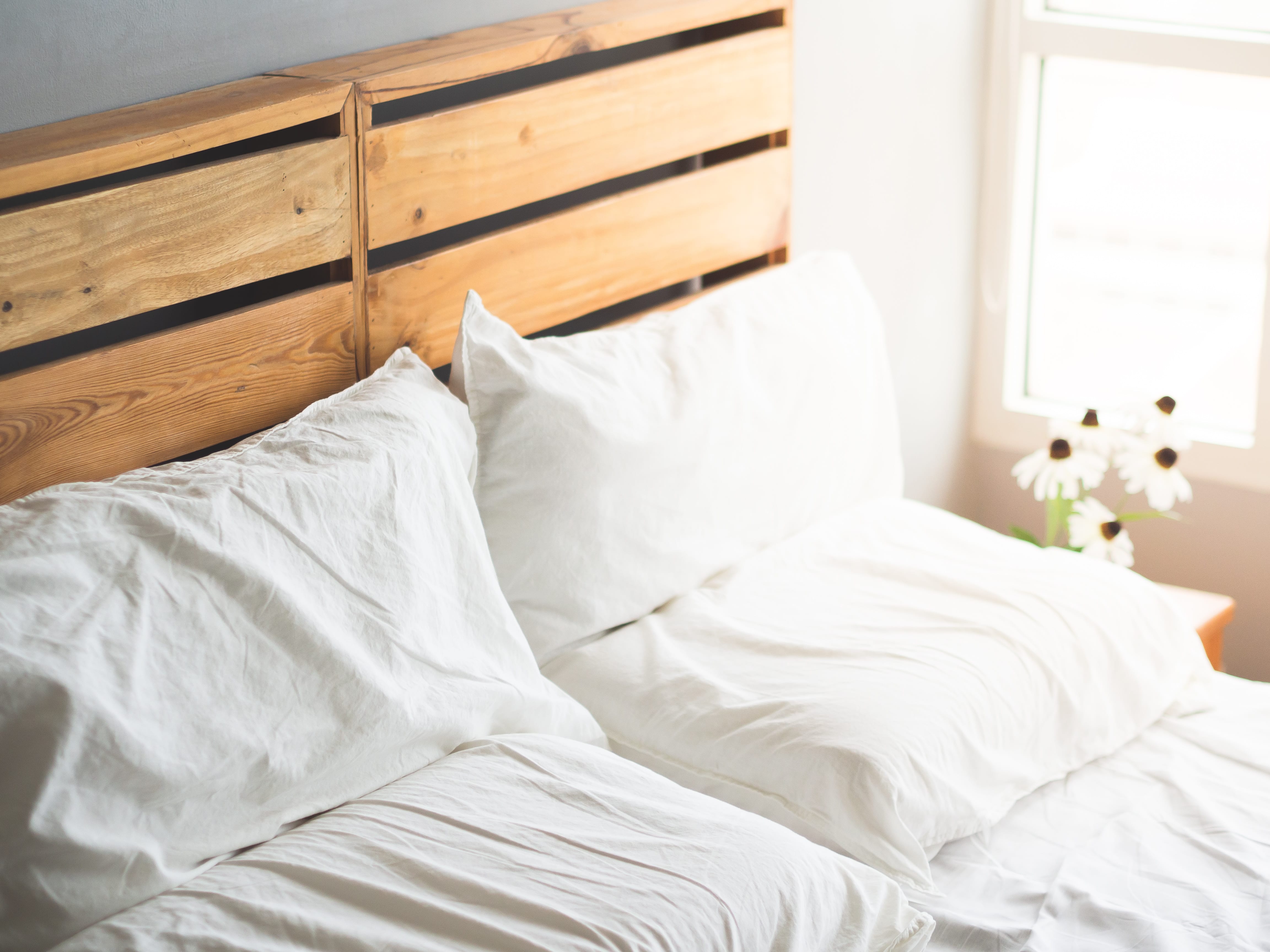 A light and airy bedroom with a bed and headboard made from wood pallets