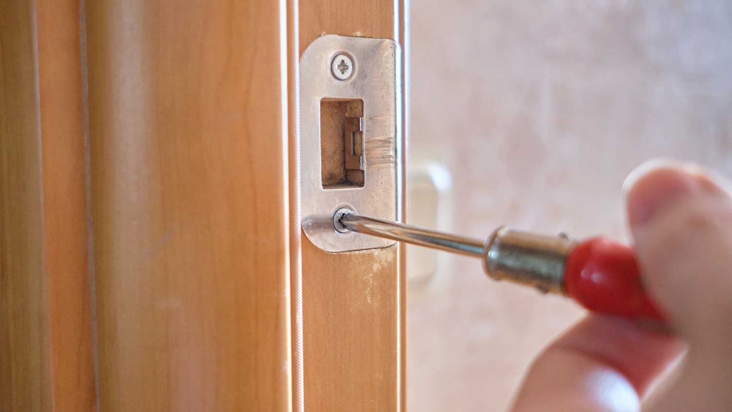 Handyperson removing full lip strike plate from a door