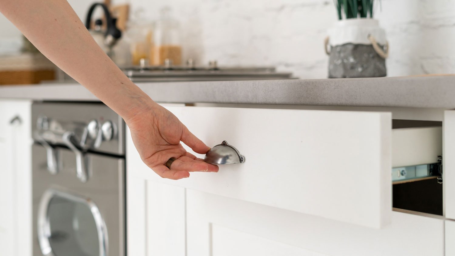 A woman opening a drawer featuring a bin pull