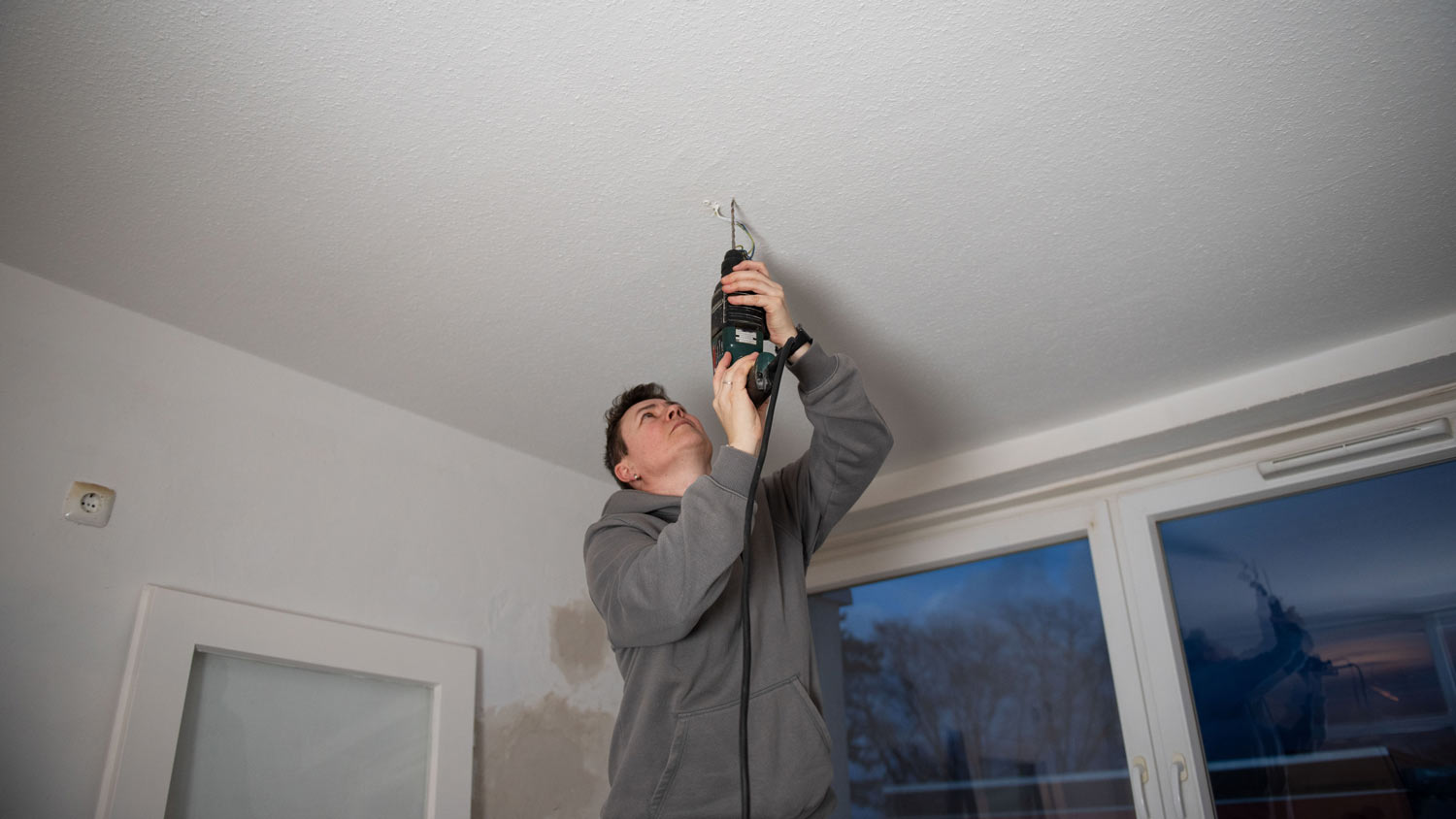 man drilling into ceiling for light fixture