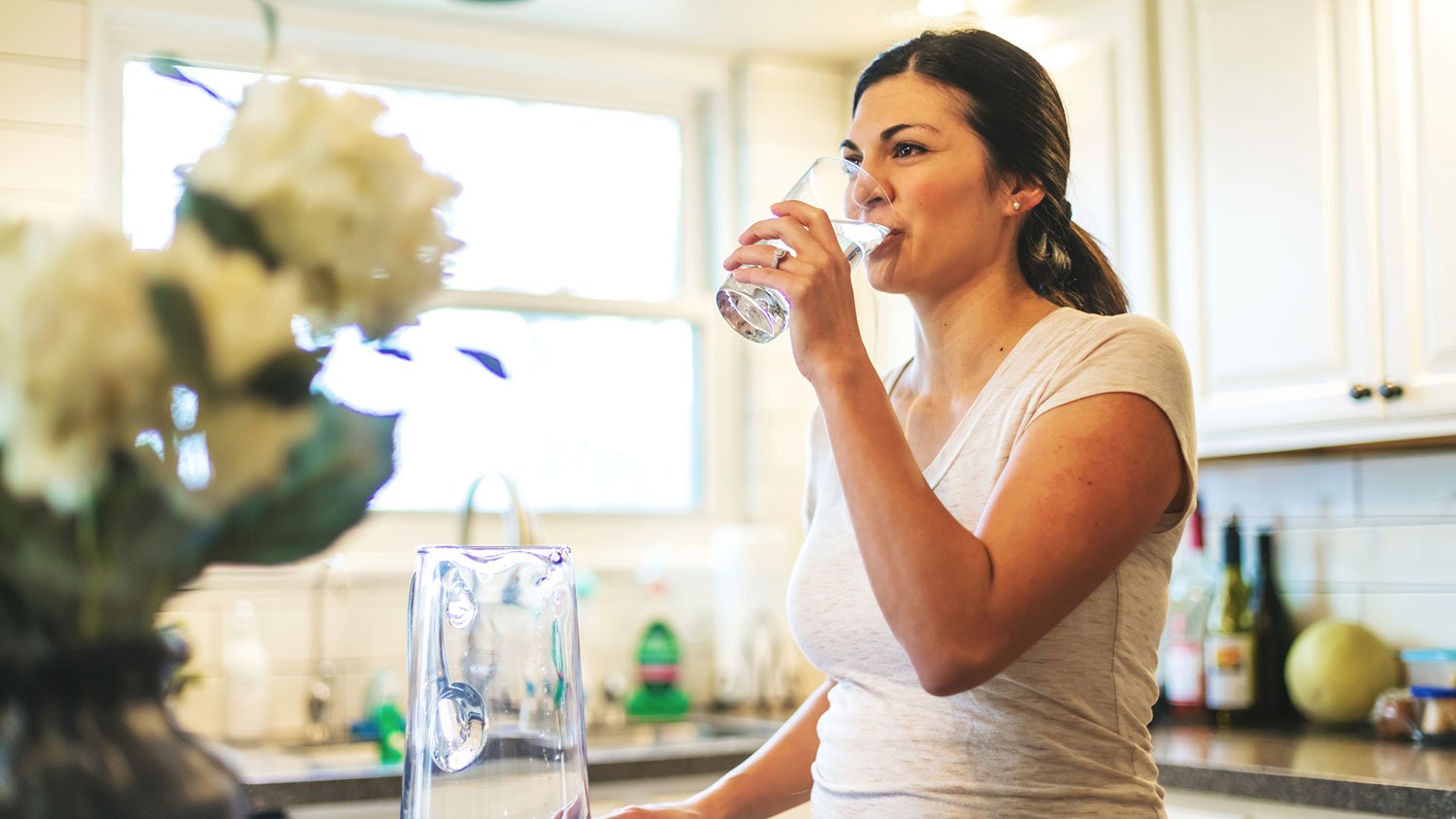 Woman in the kitchen drinking water