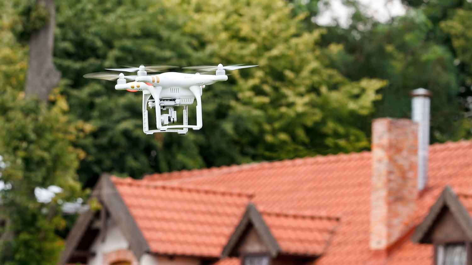 Drone with camera flying over the roof of a house