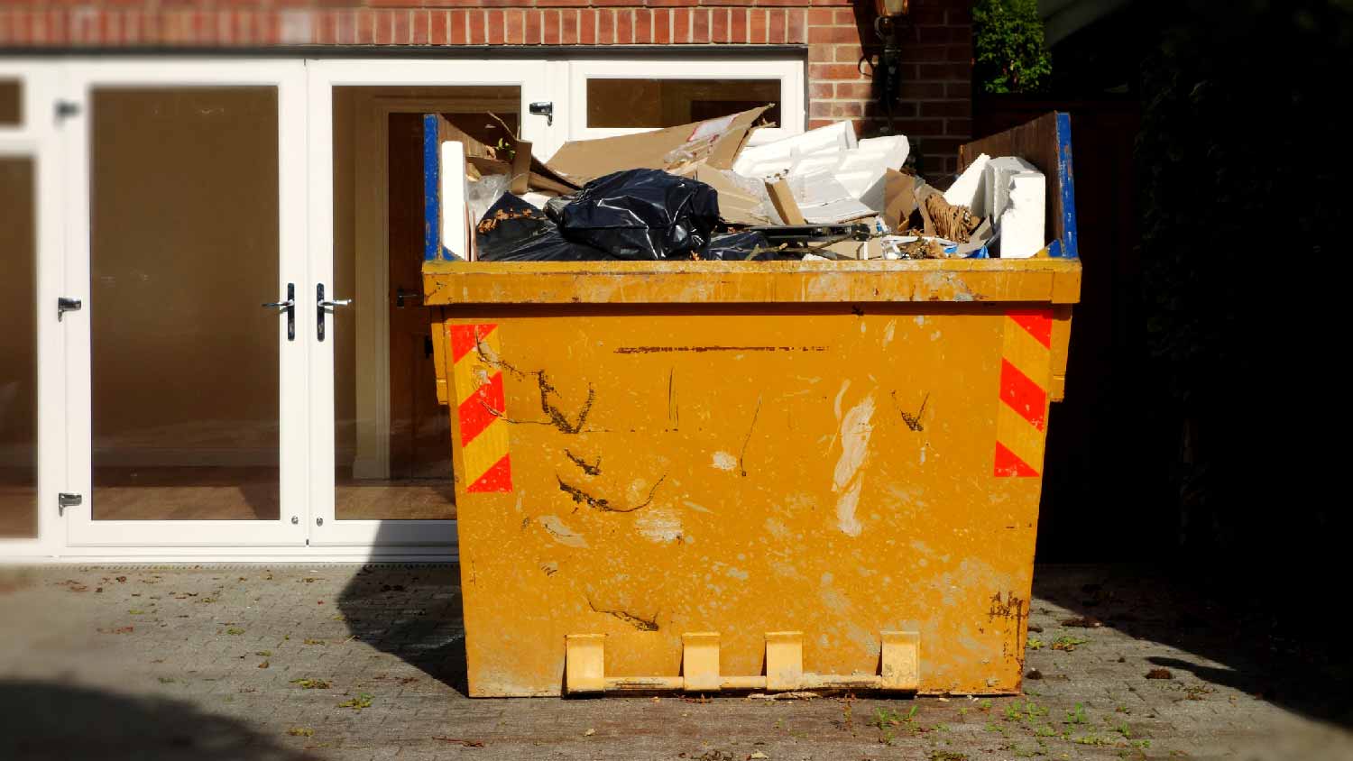 A dumpster in the front yard of a house