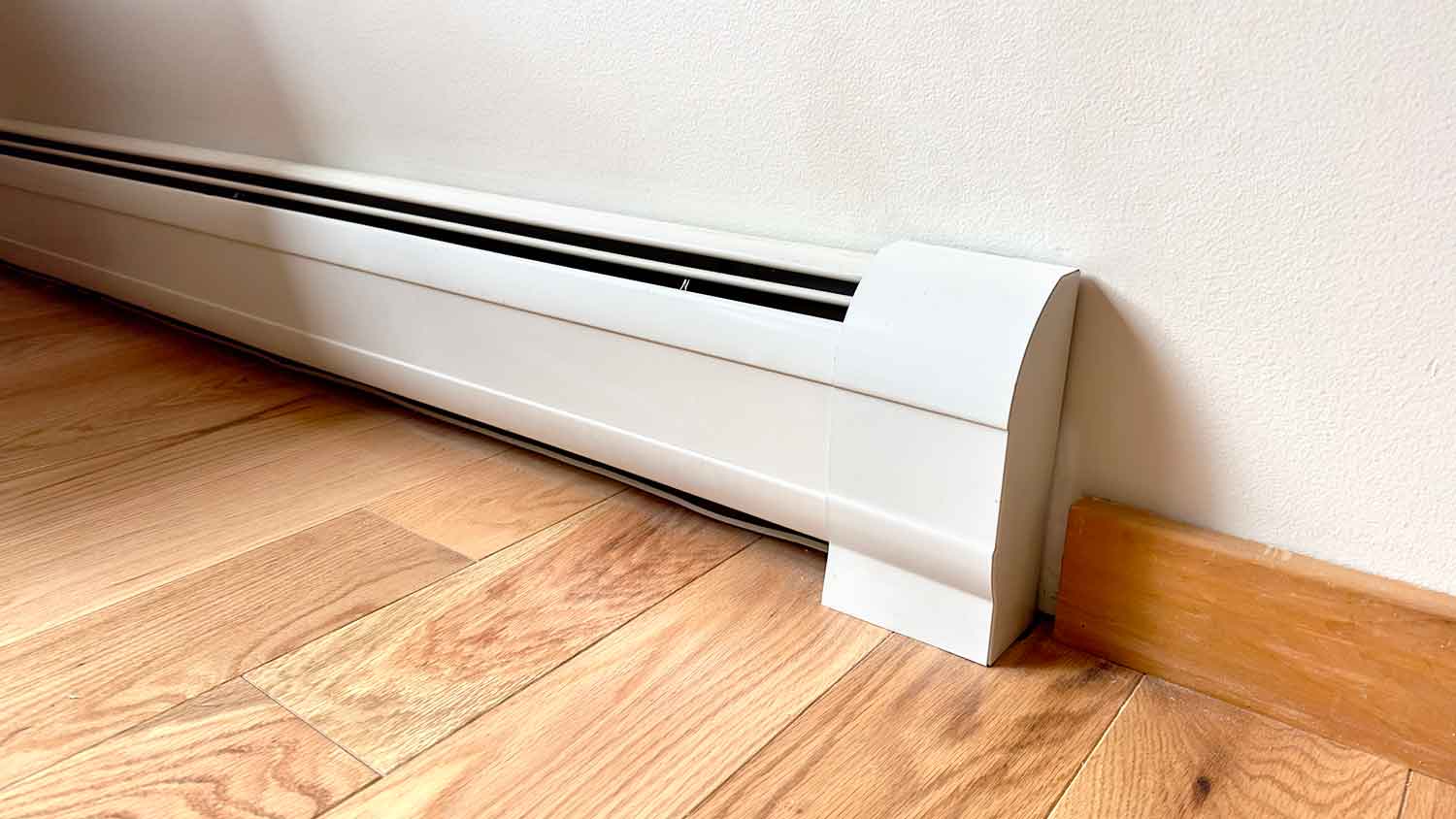 Closeup of an electric baseboard heater installed in the room