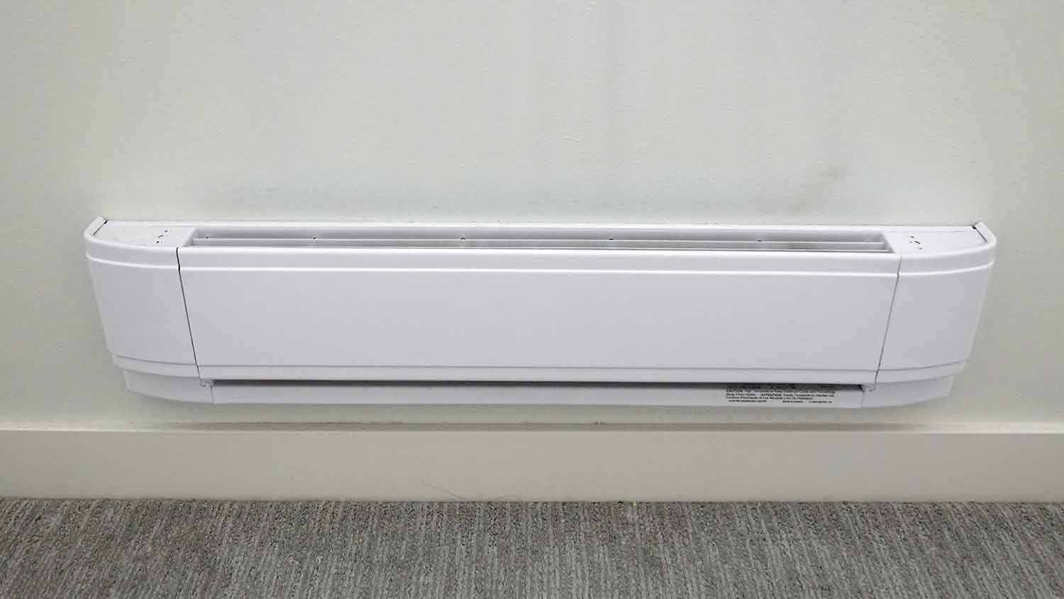 Electric baseboard heater mounted along the baseboard of a room