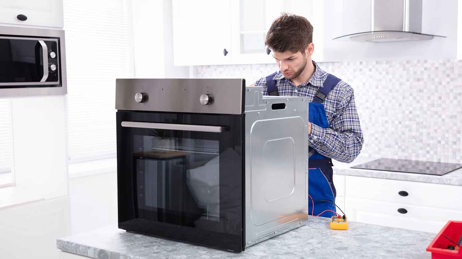 Technician in the kitchen repairing electric oven