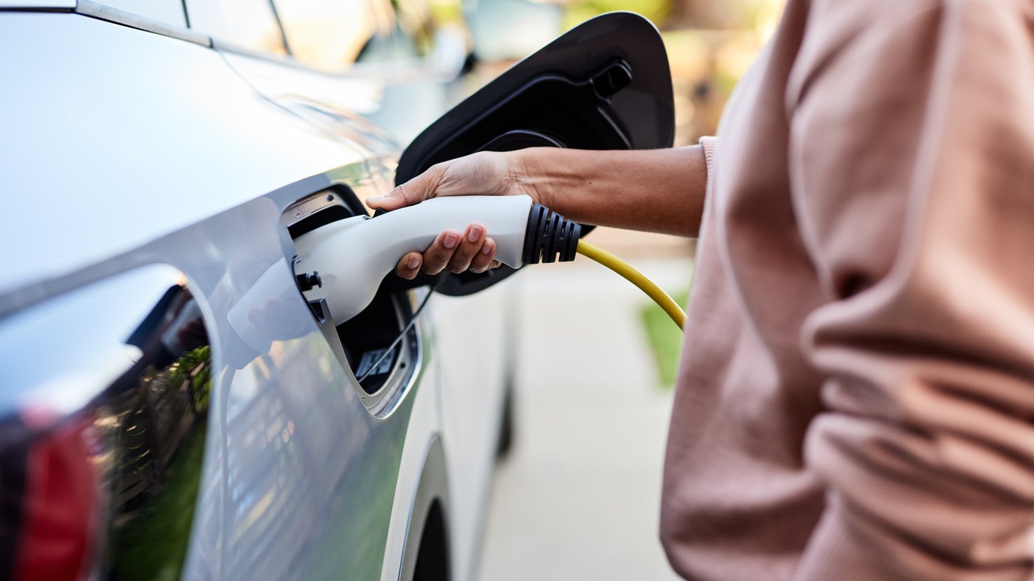 woman plugging cable in electric car