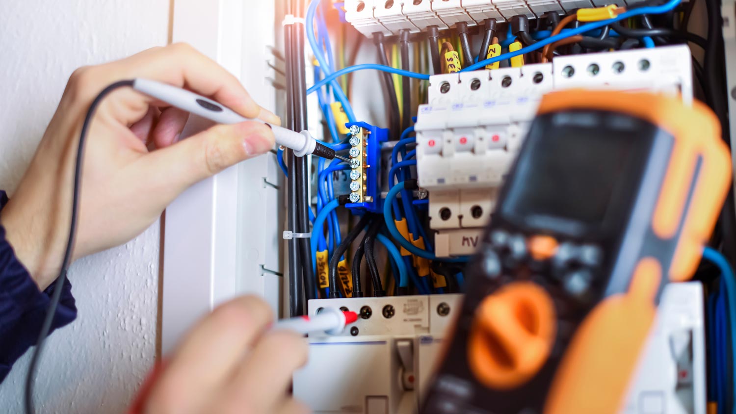 An electrician installing cables in a fuse box