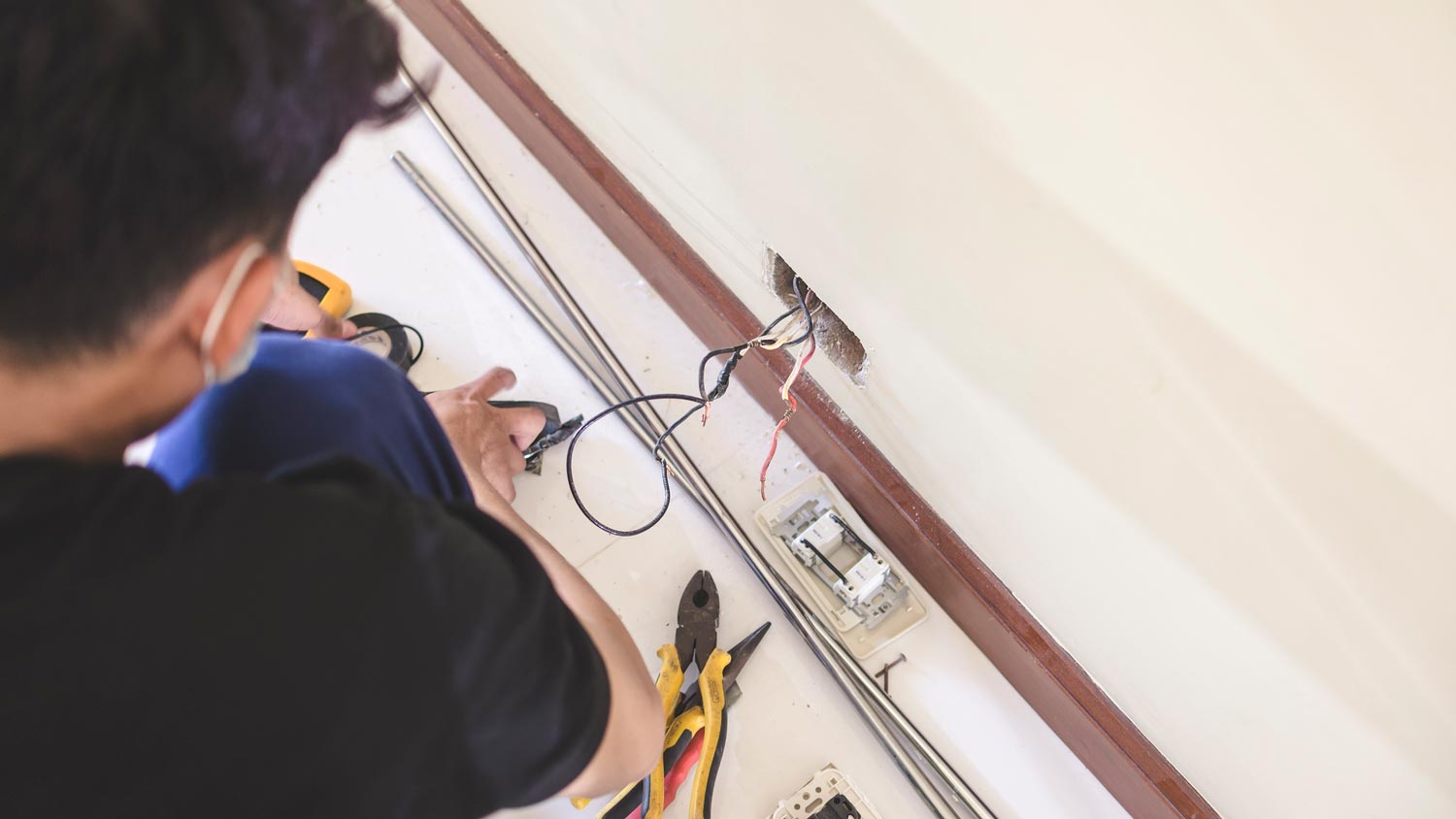 An electrician replacing an outlet on the wall