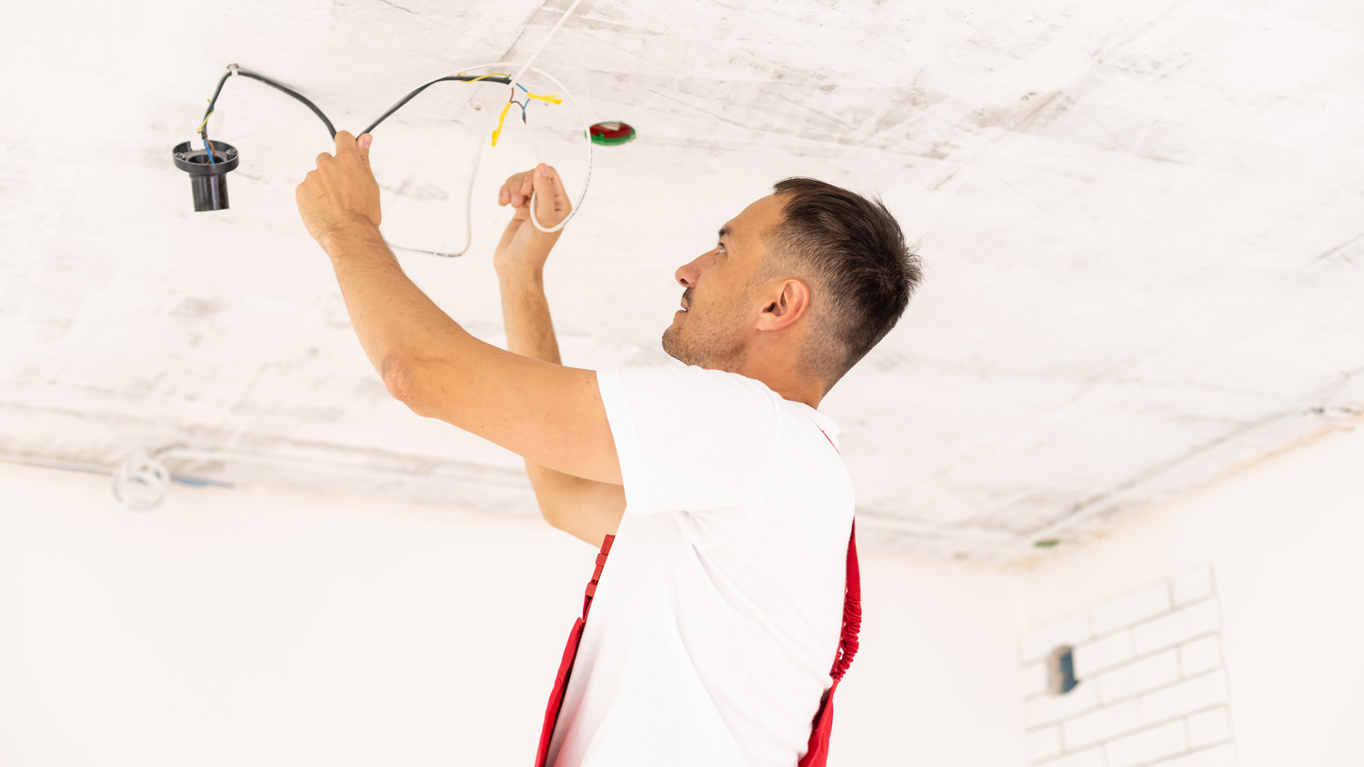 An electrician running wires in the ceiling of a room