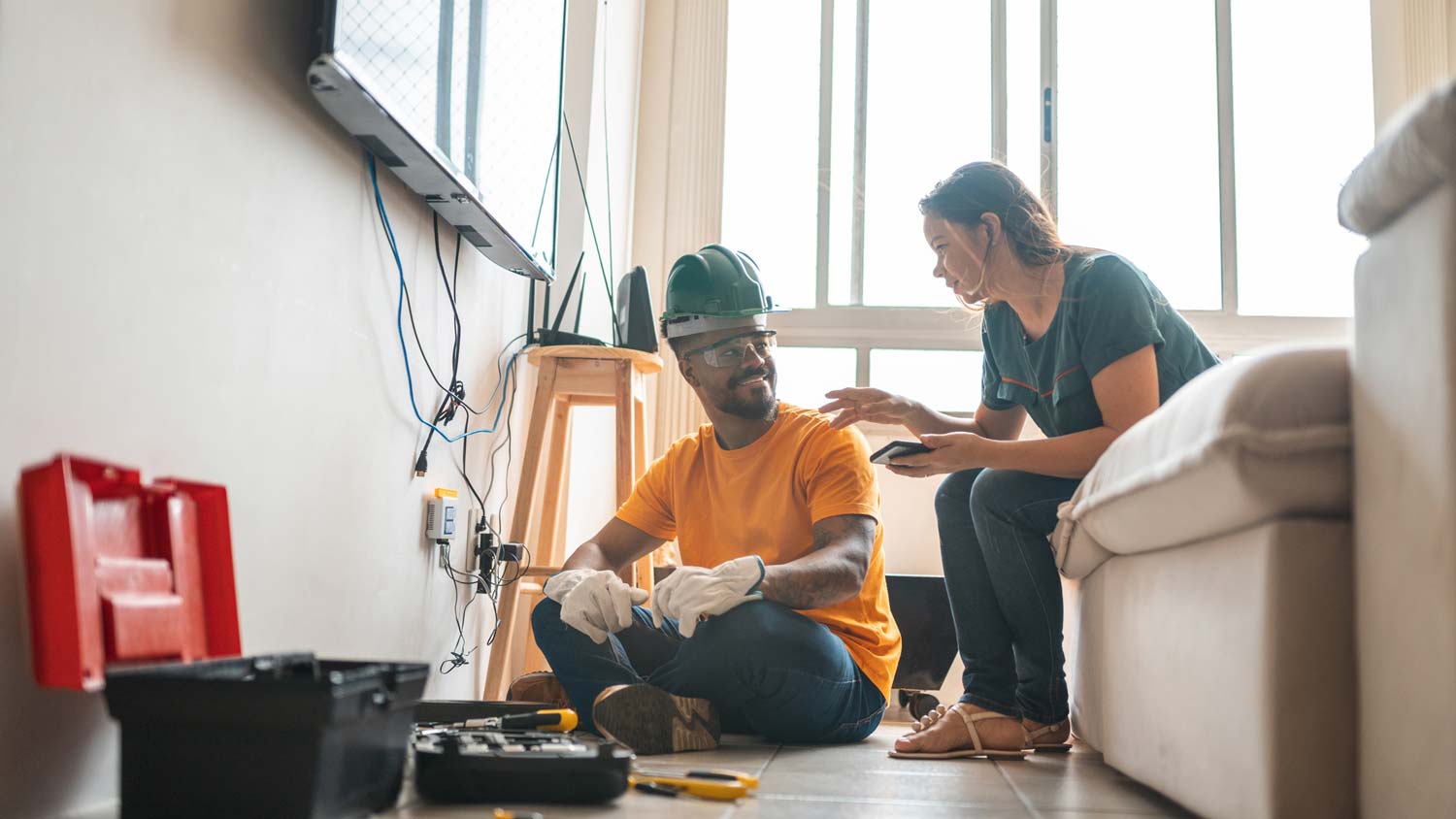 An electrician working while talking to a home owner