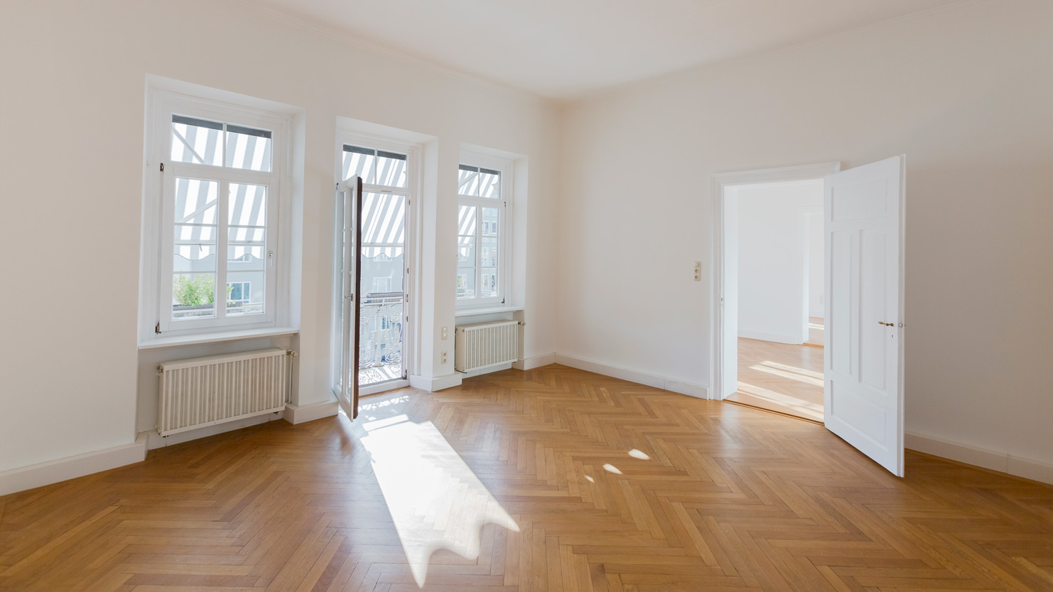 An empty room with herringbone parquet