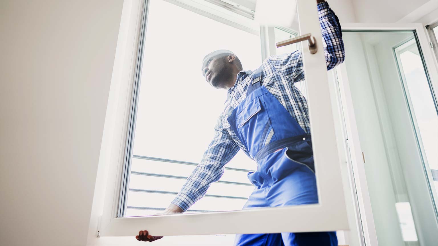 Young Repairman In Overalls Installing New Window