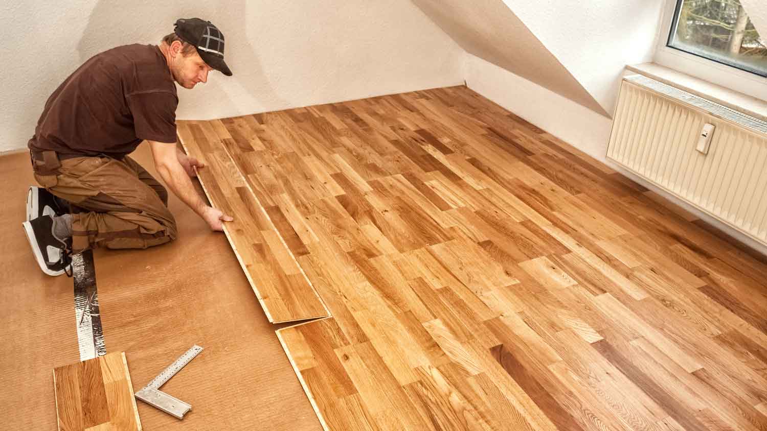 Worker installing engineered wood flooring