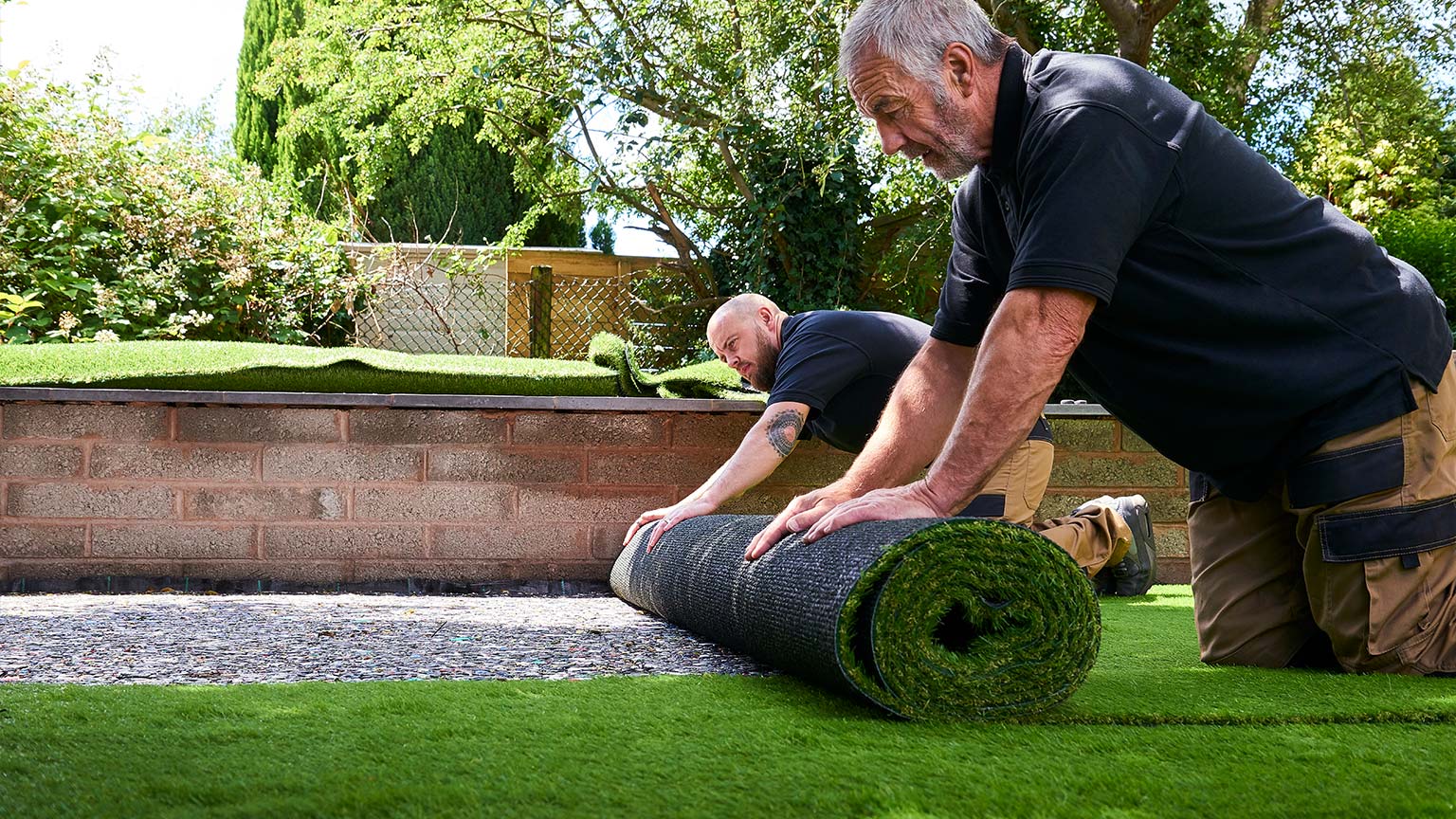 Two workers Installing artificial grass in modern garden of home