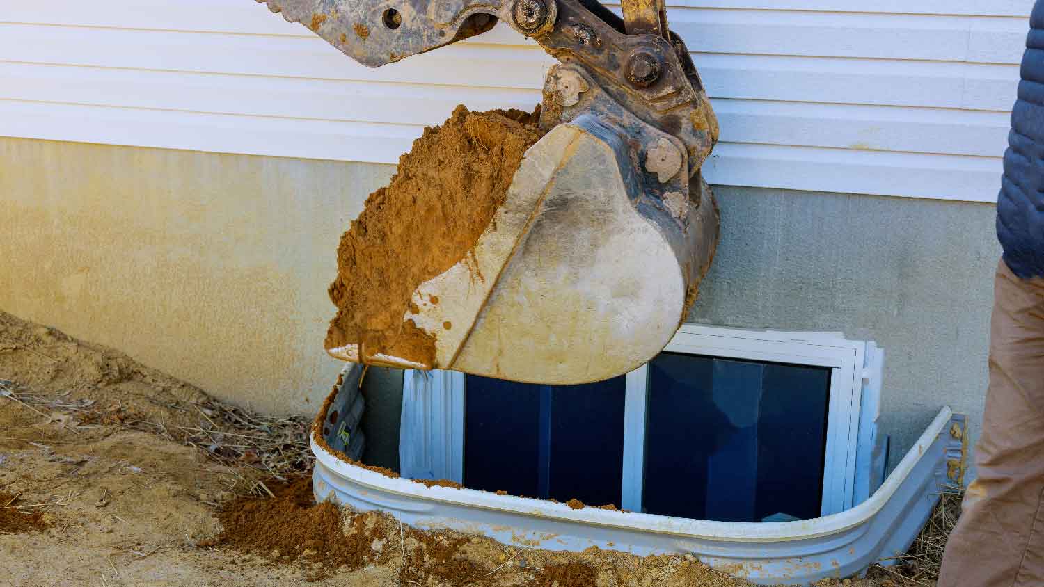 An excavator removing debris from window well 