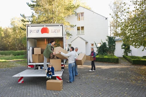 family unload boxes from moving truck to