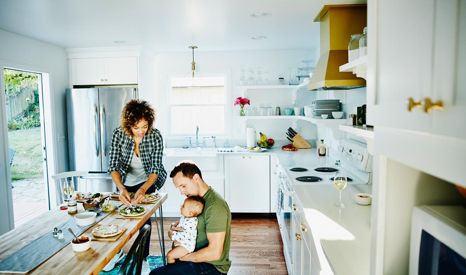 Family prepares dinner while dad holds baby