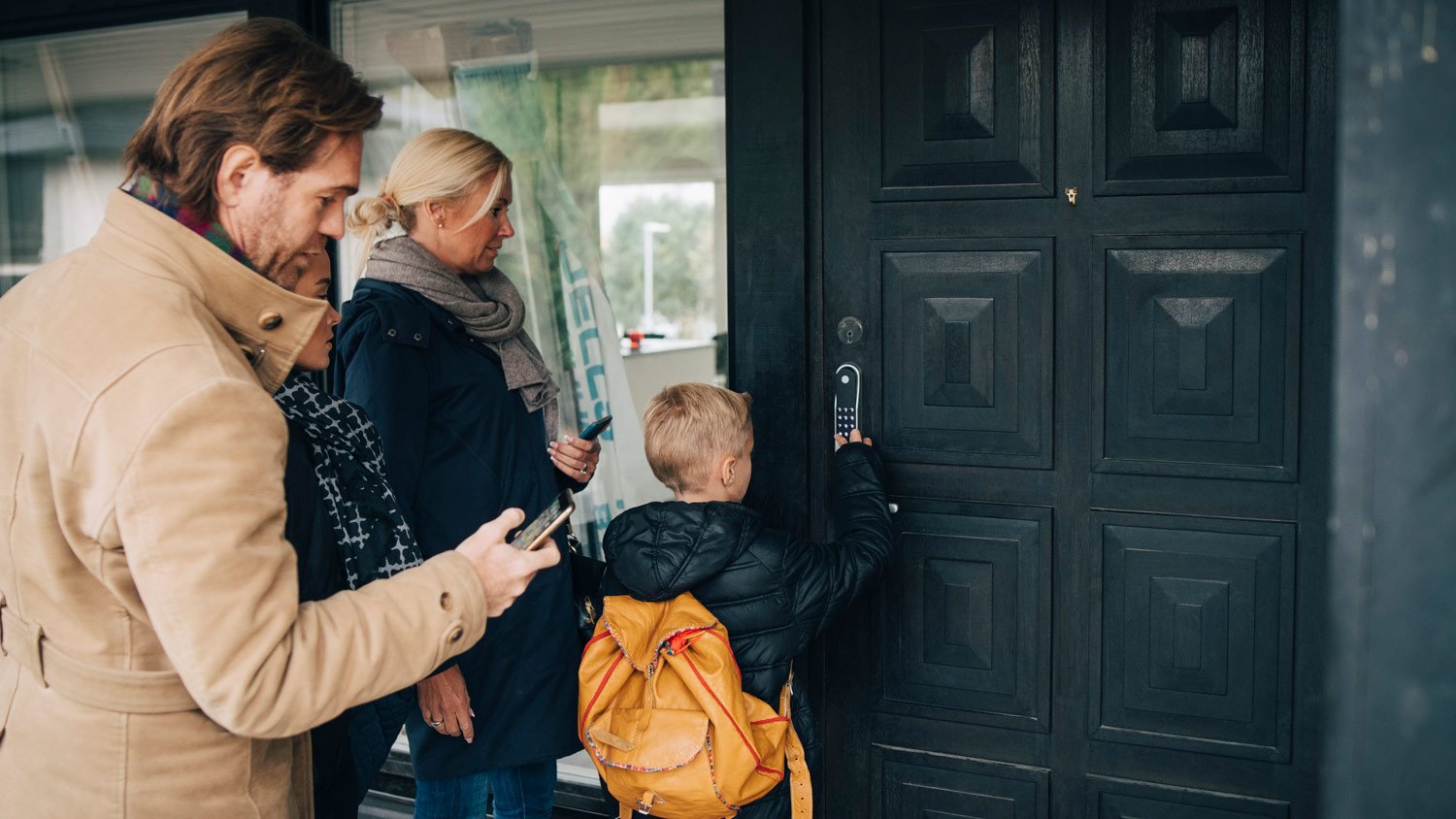 A family unlocking the front door by using a combination code