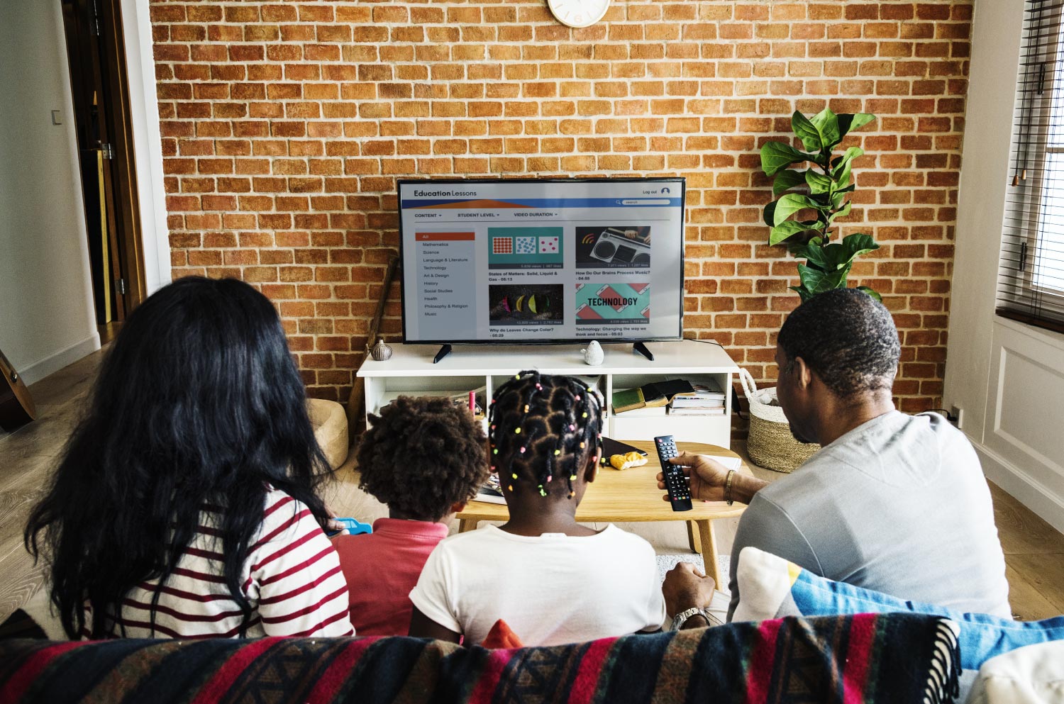 Family of four watching television together from couch