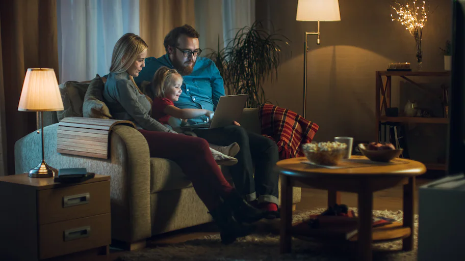 family watching a laptop on the couch at night in living room